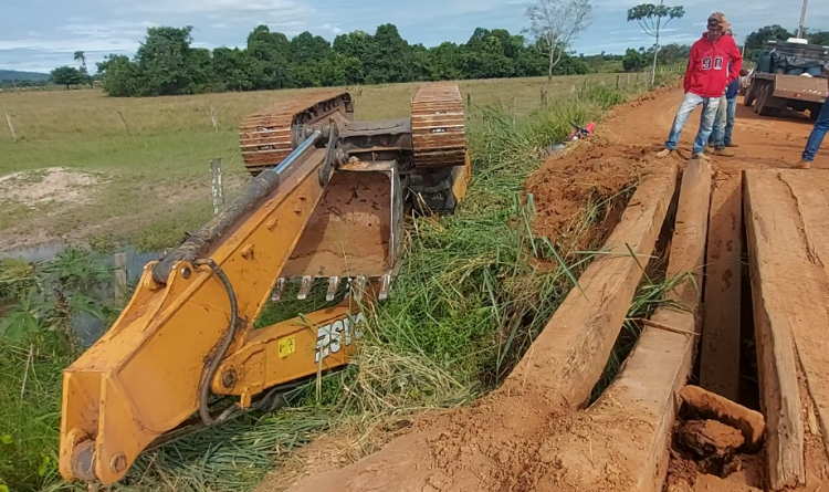 Ponte quebra e máquina pesada cai de caminhão prancha na Zona Rural